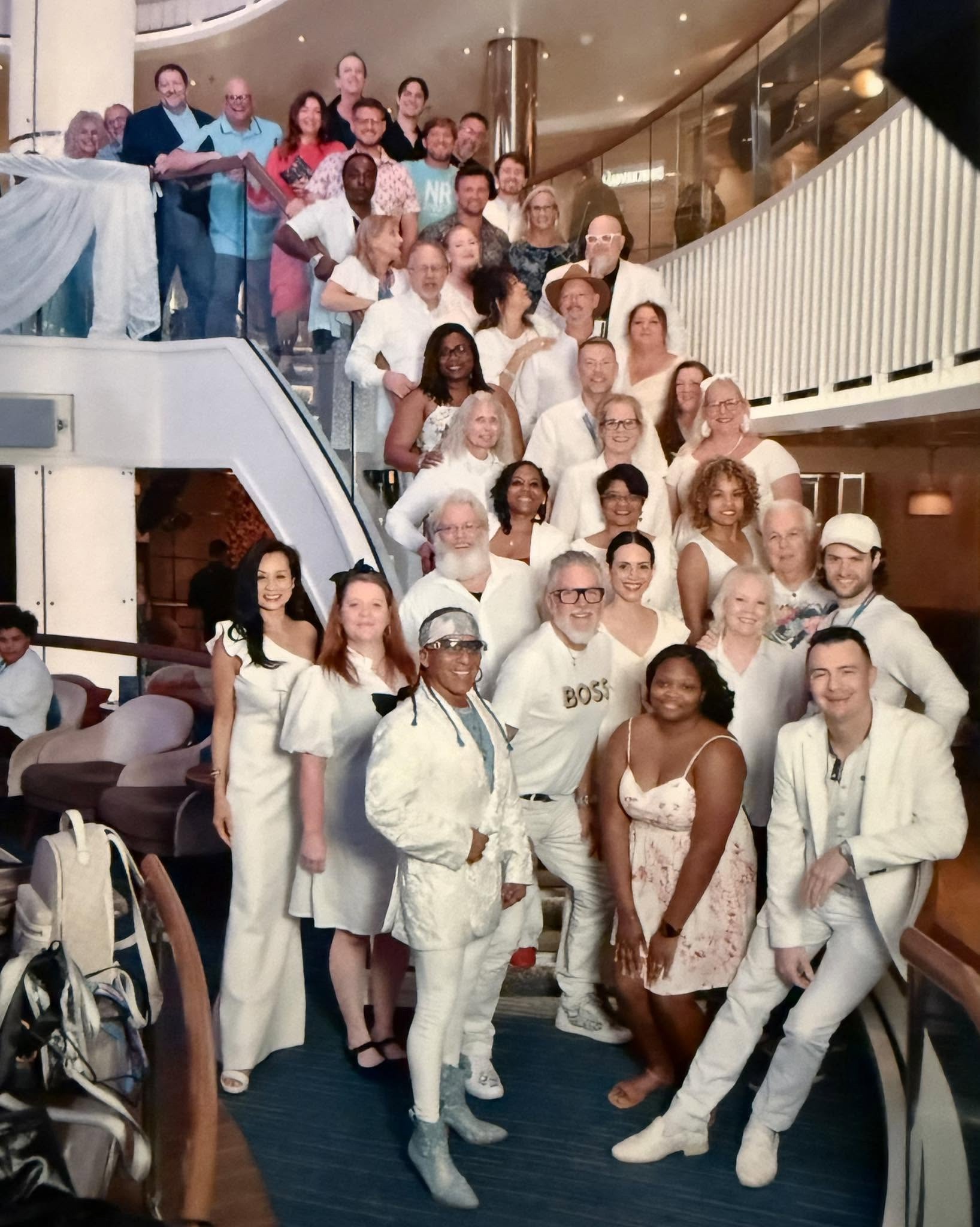 Dreamers Cruise guests dressed in white and gathered on a ship's staircase